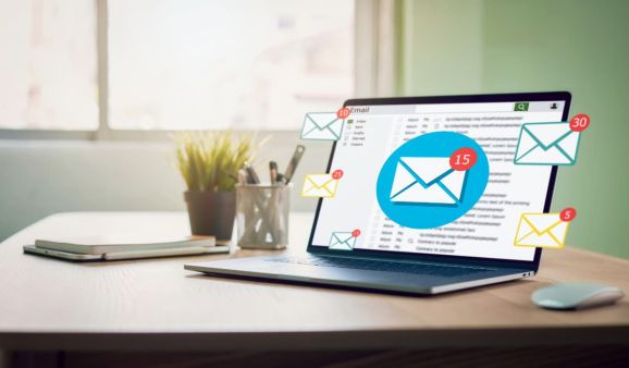 Laptop on a desk with floating email icons and notification badges around the screen