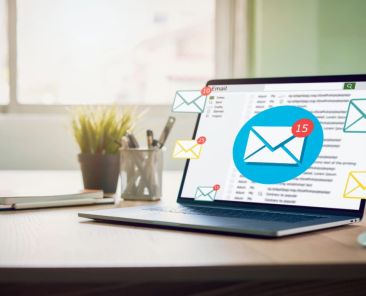 Laptop on a desk with floating email icons and notification badges around the screen