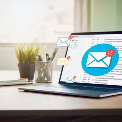 Laptop on a desk with floating email icons and notification badges around the screen.